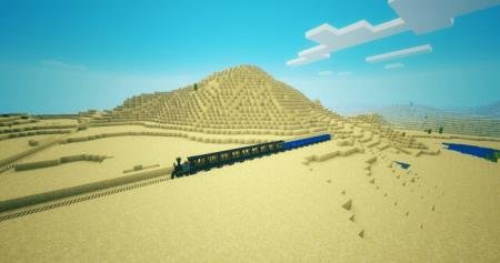 Длинный поезд с множеством синих вагонов пересекает пустыню