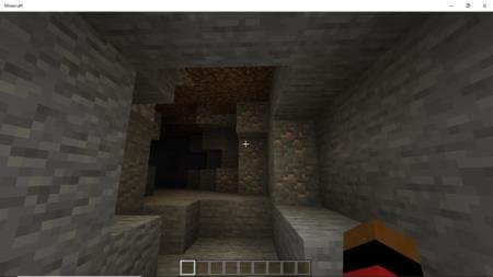 Игрок в шлеме шахтёра освещает себе путь в пещере с золотой рудой