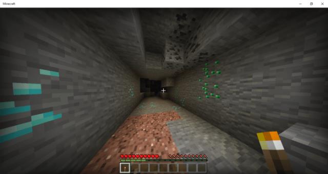 Игрок с факелом в руках освещает свой путь к рудам в пещере