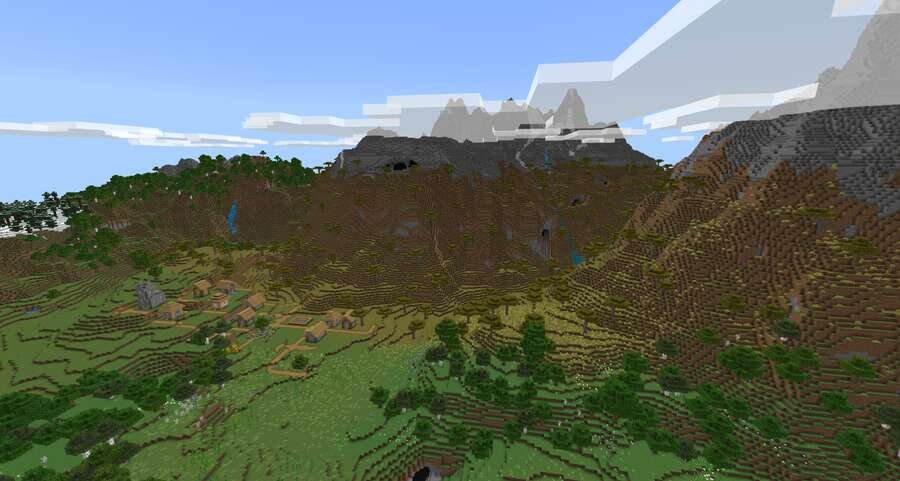 Вид на мощные горные гряды и поле с деревней