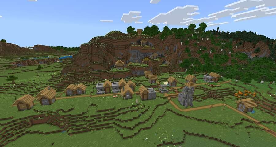 Деревушка на зеленом поле на фоне высоких гор